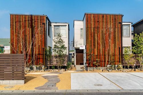 two tall buildings with trees in front of them at Rakuten STAY HOUSE x WILL STYLE Hachimanbori in Omihachiman