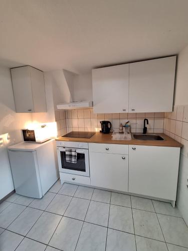 a white kitchen with white cabinets and a sink at Helmstedt City Apartment in Helmstedt