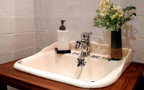a bathroom sink with a vase of flowers on it at Casa Rural Alcancia in Consuegra