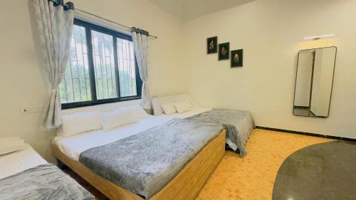 two twin beds in a room with a window at Riveredgemanor in Pālghar