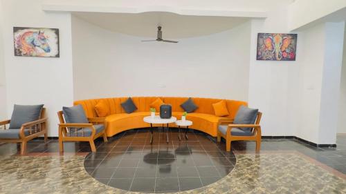 an orange couch in a room with chairs and a table at Riveredgemanor in Pālghar