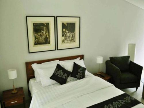 a bedroom with a bed with a chair and pictures on the wall at VillaTel Salse in Bandung