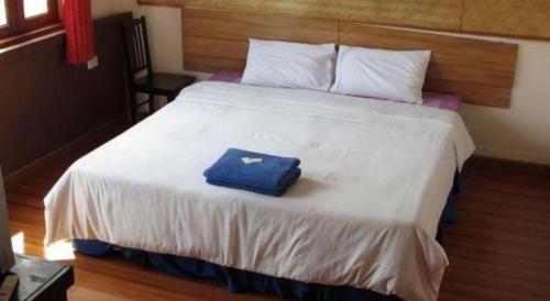 a large white bed with a blue bag on it at Sritrang Hotel in Trang