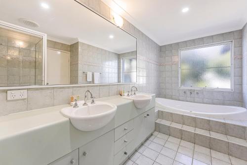 a bathroom with two sinks and a tub and a mirror at Mandurah Quay Resort in Mandurah