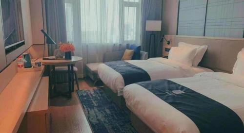a room with two beds and a table and a window at Echarm Hotel Guilin North High Speed Railway Station in Guilin