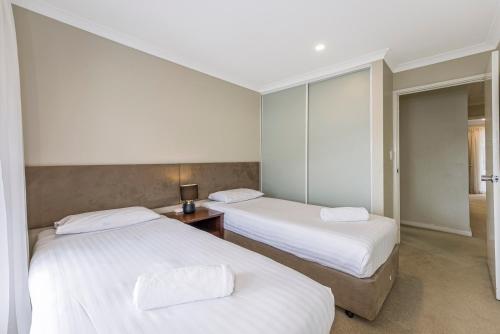 two beds in a room with white sheets at Mandurah Quay Resort in Mandurah