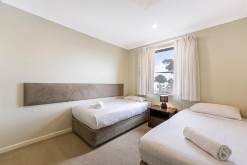a bedroom with two beds and a window at Mandurah Quay Resort in Mandurah