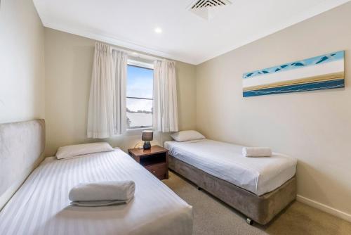 two beds in a small room with a window at Mandurah Quay Resort in Mandurah