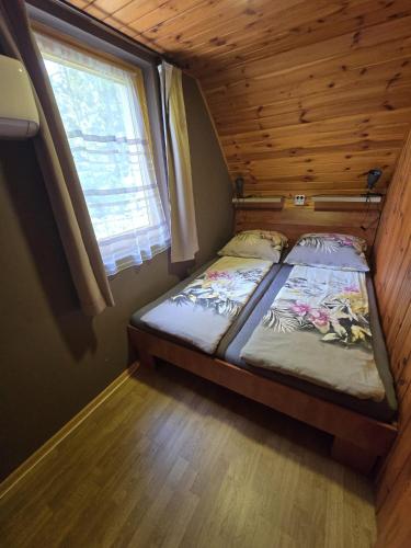 a small bedroom with two beds in a cabin at Adler vendégház horgász nyaraló in Gyomaendrőd