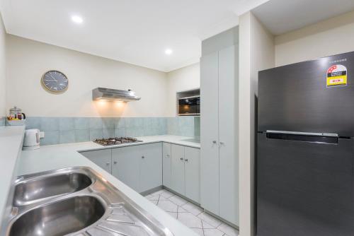 a kitchen with a sink and a refrigerator at Mandurah Quay Resort in Mandurah