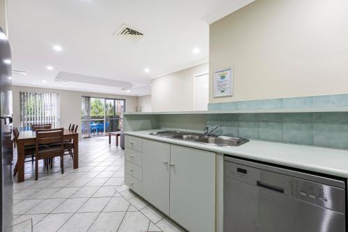 a kitchen with a sink and a table with chairs at Mandurah Quay Resort in Mandurah