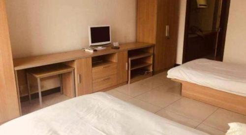 a bedroom with a desk with a computer on it at Tangshan Qiangang Hotel in Qian'an