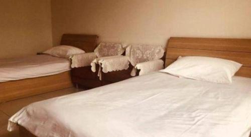 a bedroom with two beds and two chairs at Tangshan Qiangang Hotel in Qian'an