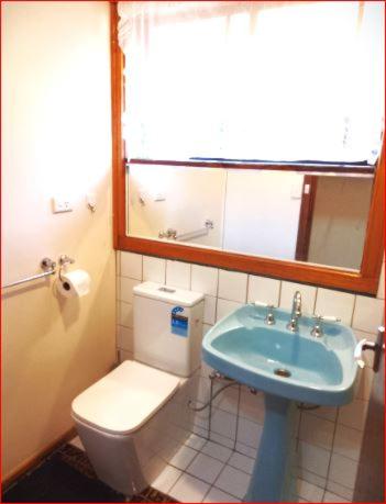 a bathroom with a toilet and a blue sink at Charming Three-Bedroom Holiday Home Near Tourist Attractions in Werribee