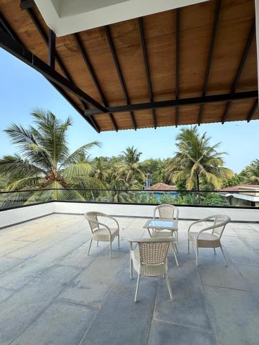 a patio with chairs and tables and palm trees at Trabalho de Amor in Benaulim