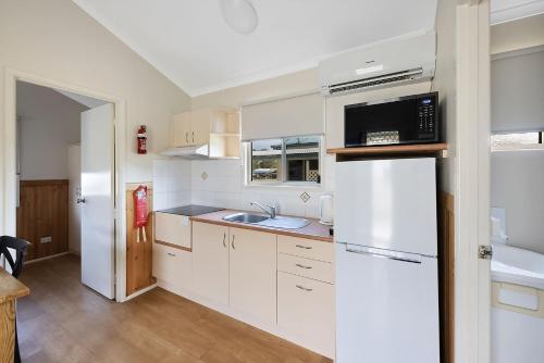 a kitchen with white cabinets and a white refrigerator at Reflections Evans Head - Holiday Park in Evans Head