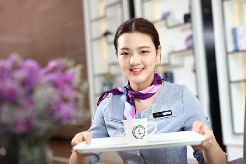a woman holding a tray with a coffee cup on it at Lavande Hotels·Qingyuan Jinbiwan in Qingyuan