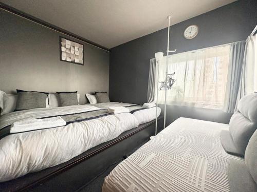 a bedroom with two beds and a clock on the wall at Ikebukuro正和庵 in Tokyo