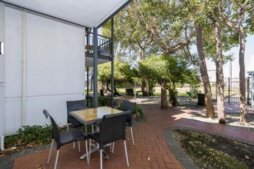 a patio with a table and chairs and trees at Mandurah Quay Resort in Mandurah