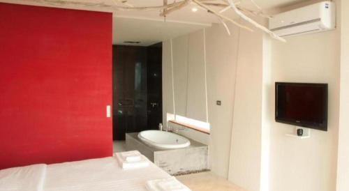 a bedroom with a red wall and a toilet and a tv at Red Z The Ocean in Phetchaburi