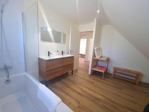 une salle de bain avec un lavabo et une baignoire dans l'établissement Maison proche de la mer, à Pénestin