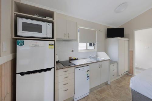 a kitchen with a white refrigerator and a microwave at Reflections Evans Head - Holiday Park in Evans Head
