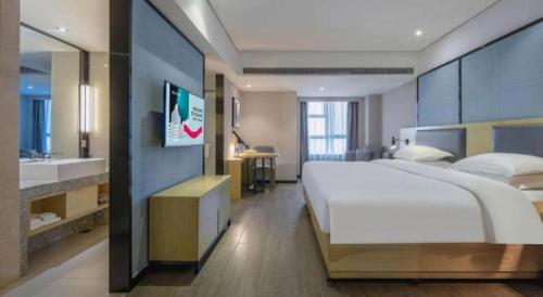a large bedroom with a large bed and a bathroom at Echarm Hotel Beihai Railway Station in Beihai