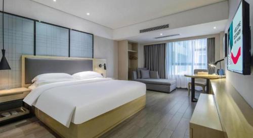 a bedroom with a large bed and a living room at Echarm Hotel Beihai Railway Station in Beihai