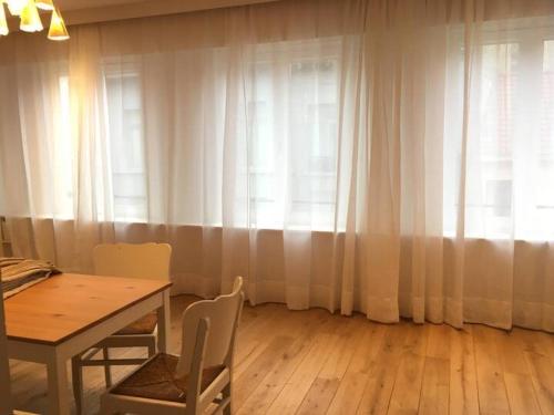 a dining room with a table and white curtains at Huswell Artsy Family Apartment in City Center in Antwerp