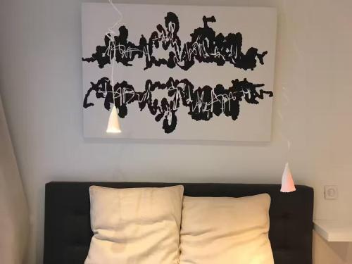 a black and white painting above a bed with a pillow at Huswell Artsy Family Apartment in City Center in Antwerp