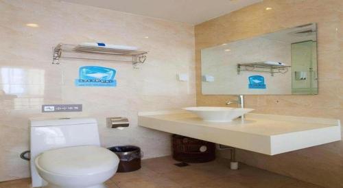 a bathroom with a toilet and a sink and a mirror at 7 Days Inn Tianjin Development Zone 3rd Street Wanli in Binhai