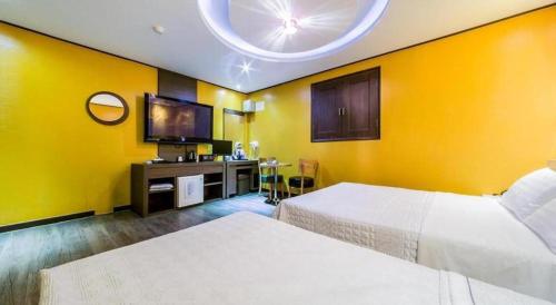 a hotel room with two beds and a flat screen tv at Seven Motel Ansan in Ansan