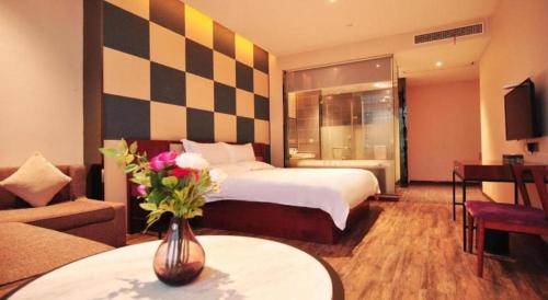 a hotel room with a bed and a vase of flowers at Hangzhou Berman Hotel in Hangzhou