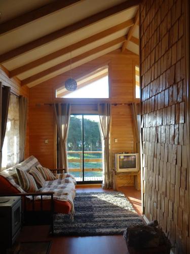 a living room with a couch and a large window at Cabañas Torre Huillinco in Huillinco