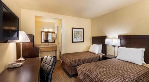 a hotel room with two beds and a flat screen tv at Lemon Heights Inn in Tustin