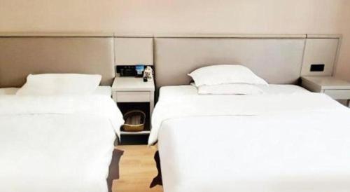 a room with two beds and a telephone in it at GreenTree Inn Fuyang Yijing International North Business in Fuyang