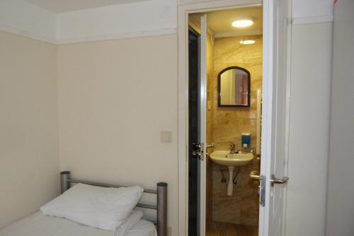 ブダペストにあるCenter Hostel and Guest Houseのベッドルーム(ベッド1台、シンク、鏡付)