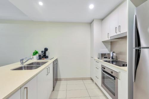 a kitchen with white cabinets and a refrigerator at Harbour View Suite in Darwin