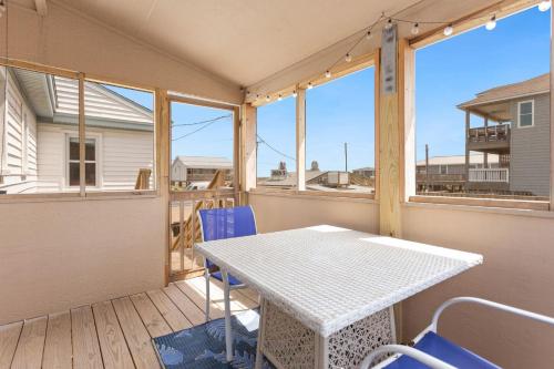 a table and chairs on a balcony with windows at 4119 - The Dolphin Boat in Kitty Hawk