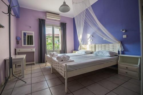 a bedroom with a large bed with purple walls at Potamaki Studios & Apartments in Stoupa