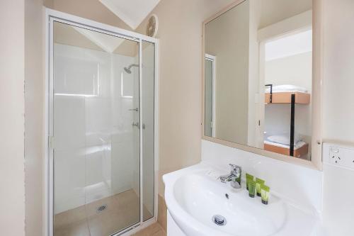 a white bathroom with a shower and a sink at Reflections Evans Head - Holiday Park in Evans Head