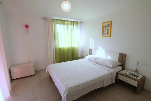 a bedroom with a white bed and a green curtain at Apartments Lucefinka in Banjole