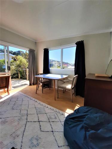 a living room with a table and chairs and windows at Peace and quiet in the Brooklyn hills in Wellington