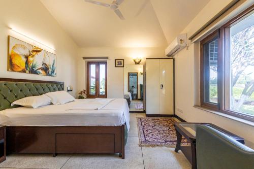 a bedroom with a bed and a desk and a window at De Vivendi Farm- A Rural Luxury Farmhouse Getaway in Bahora