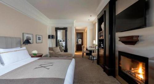a bedroom with a fireplace and a bed and a living room at Fifteen Beacon Hotel in Boston