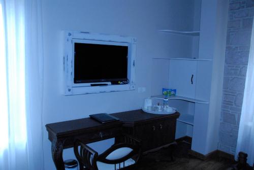 a room with a desk with a television on a wall at Orchis Hotel in Ayvalık