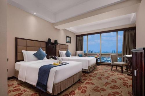 a hotel room with two beds and a large window at Changsha Huatian Hotel in Changsha