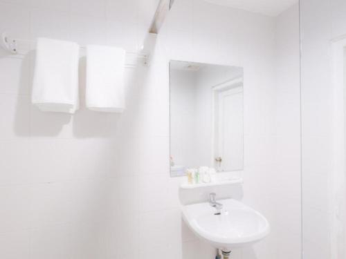 a white bathroom with a sink and a mirror at Hotel Zing Phnom Penh in Phnom Penh
