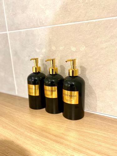 drie zwarte flessen op een houten vloer bij Luxurious 2 Bedroom - Water View and Parking in Manchester