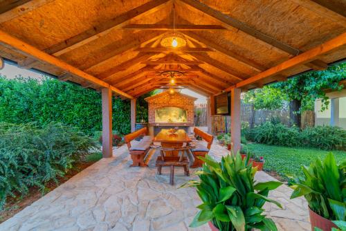 a patio with a wooden pergola with a table and chairs at Villa Lavandis with Jacuzzi and 50m2 Pool in Donji Vinjani